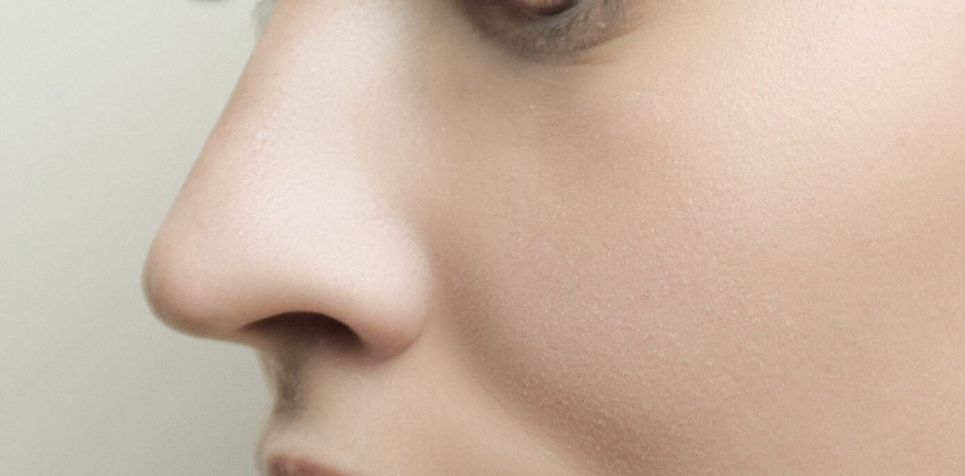 Perfil lateral detalhado do rosto de uma mulher com pele impecável e maquiagem sutil