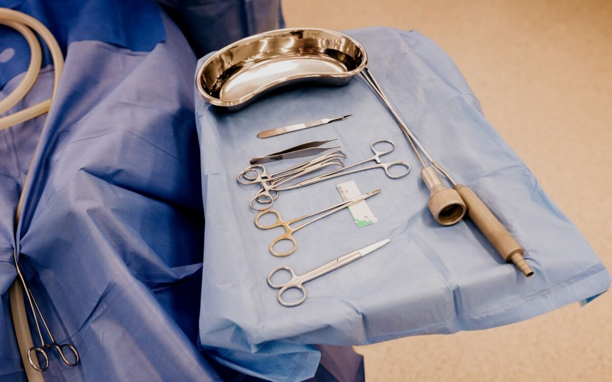 Um conjunto de instrumentos cirúrgicos dispostos em um pano azul em ambiente de sala de cirurgia estéril