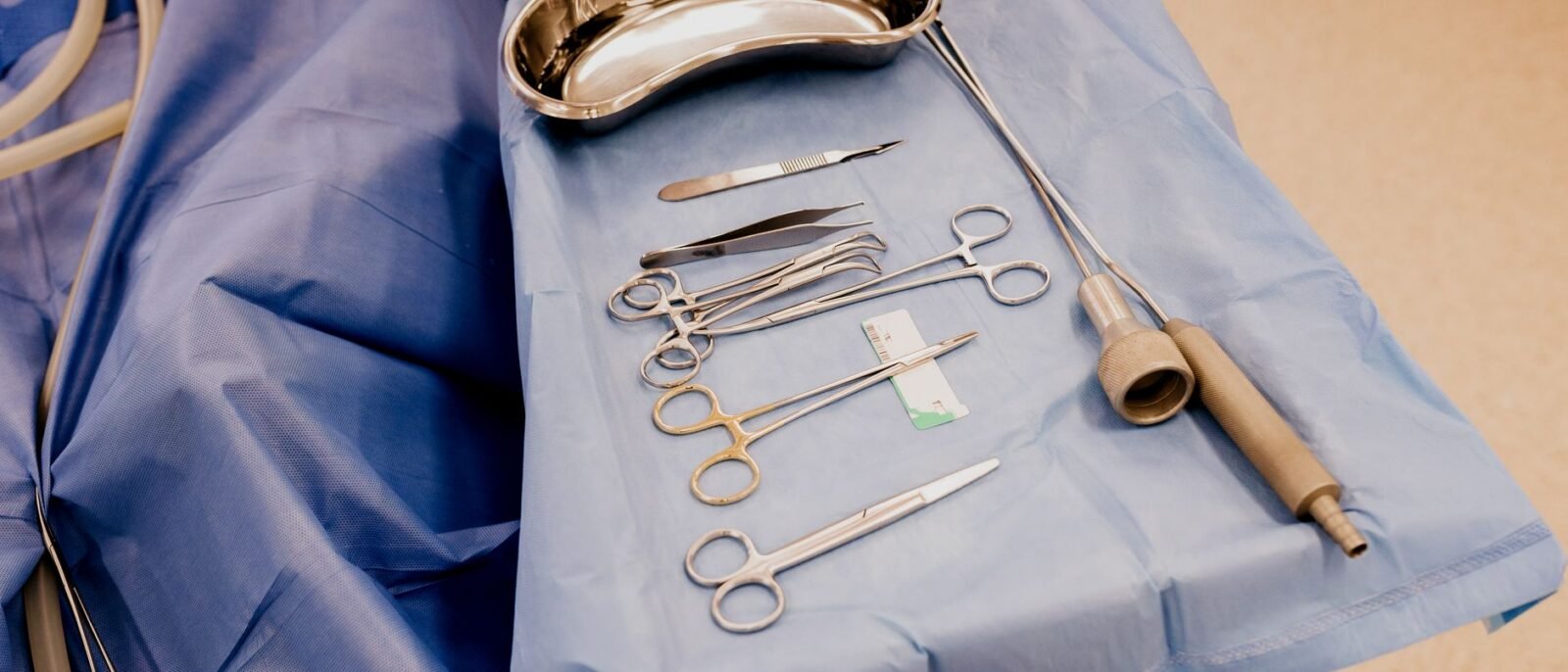 Um conjunto de instrumentos cirúrgicos dispostos em um pano azul em ambiente de sala de cirurgia estéril