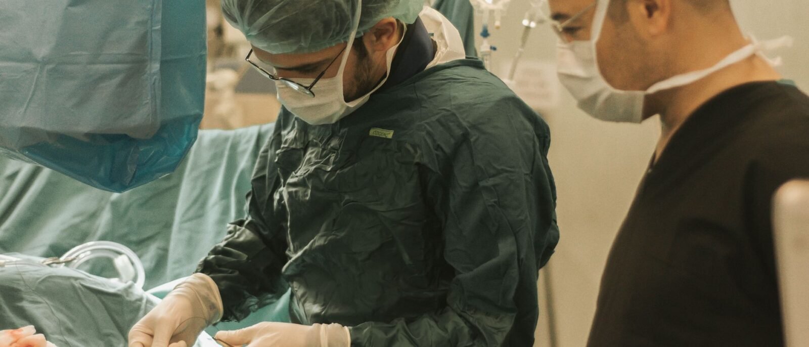 Dois cirurgiões concentrados em um procedimento médico em uma sala de operações, destacando trabalho em equipe na saúde
