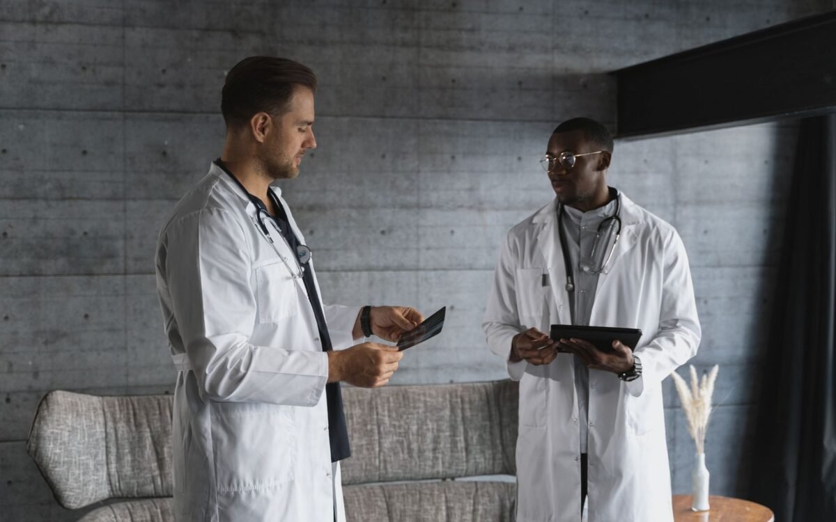 Dois médicos em um consultório médico discutindo uma radiografia, enfatizando trabalho em equipe e expertise em saúde