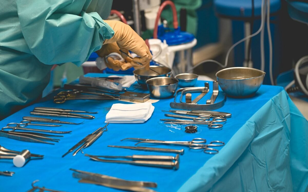 Detalhe de instrumentos cirúrgicos sobre mesa estéril durante procedimento em sala de operações de hospital