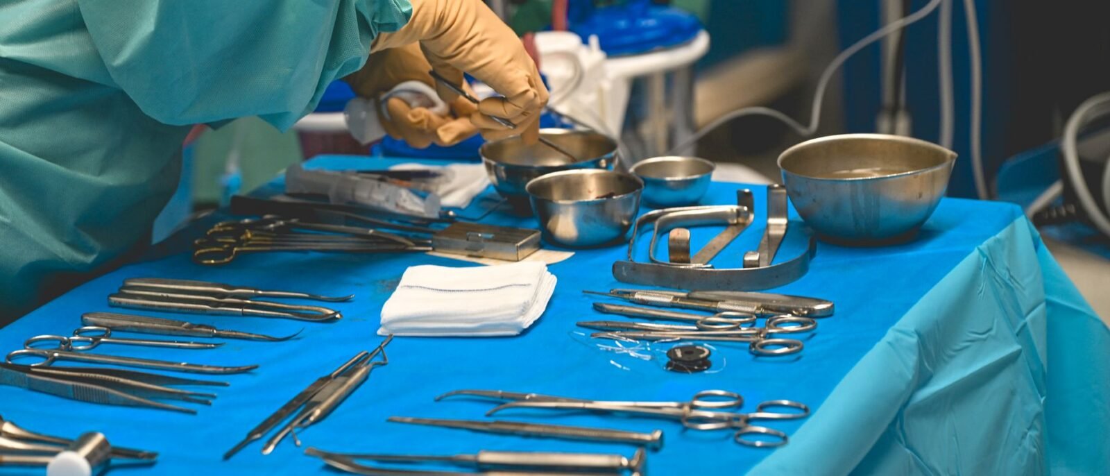 Detalhe de instrumentos cirúrgicos sobre mesa estéril durante procedimento em sala de operações de hospital
