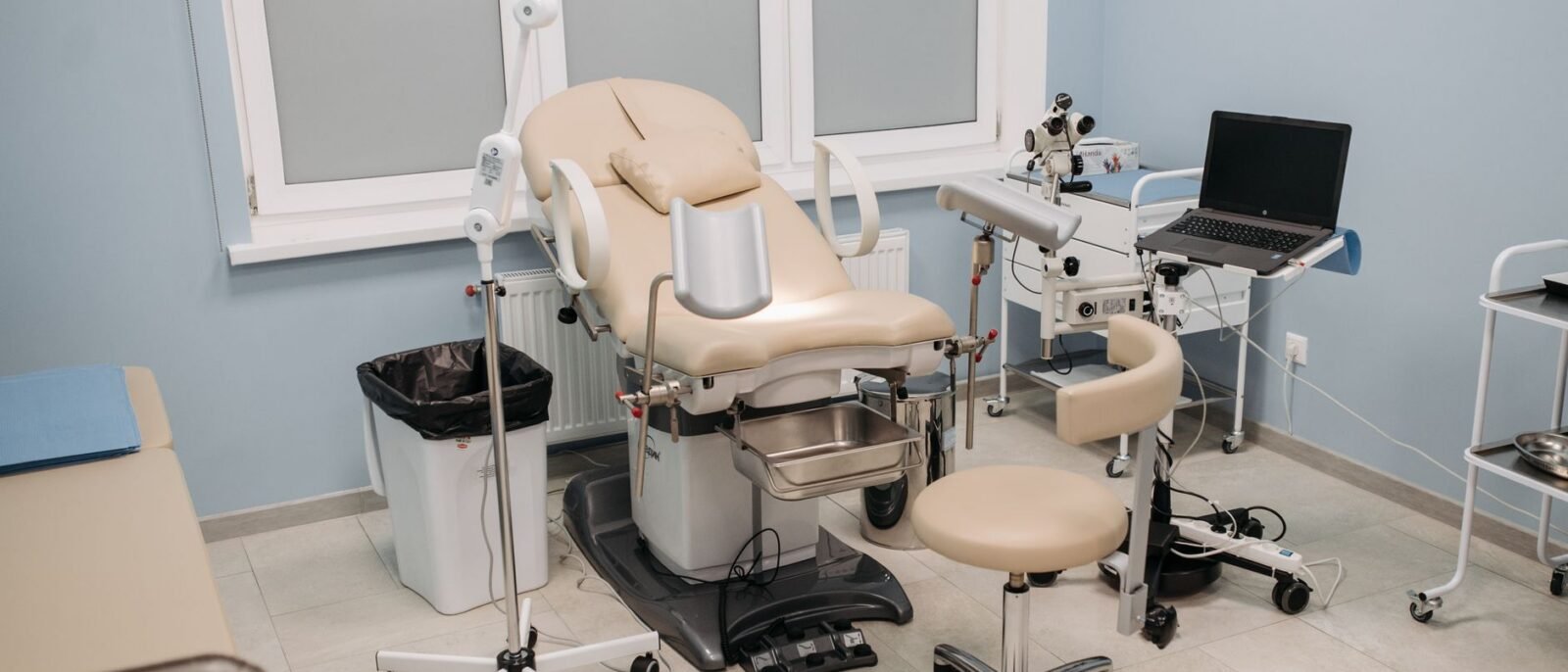 Consultório médico limpo e bem equipado com cadeira de exame e diversos instrumentos médicos