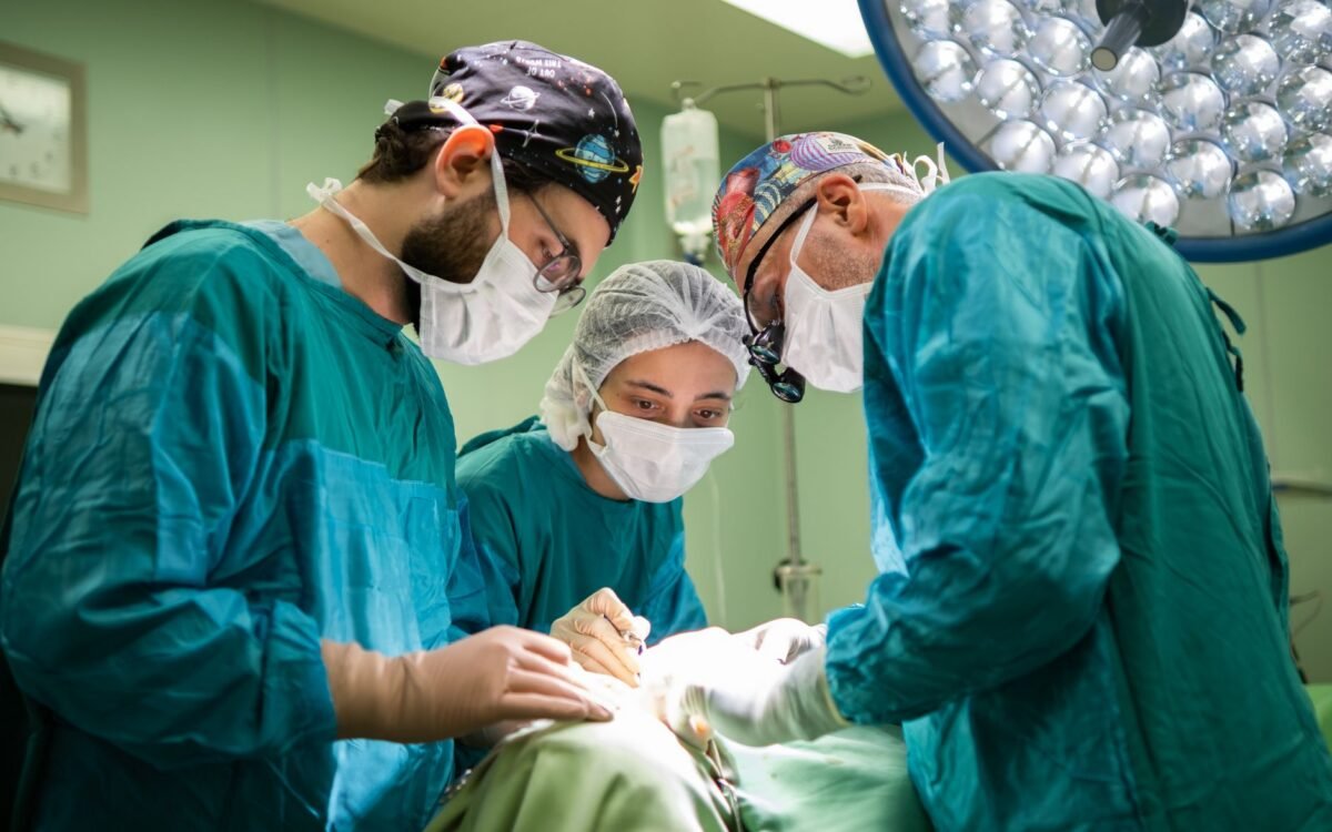 Uma equipe cirúrgica concentrada operando em uma sala de hospital bem iluminada, demonstrando trabalho em equipe e precisão