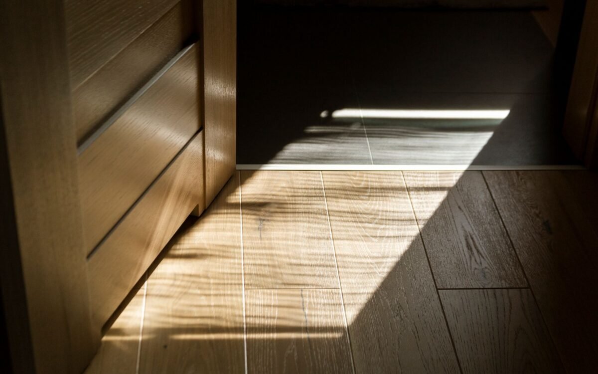 Sombras iluminadas pelo sol criam padrões em um piso de tacos de madeira em ambientes fechados