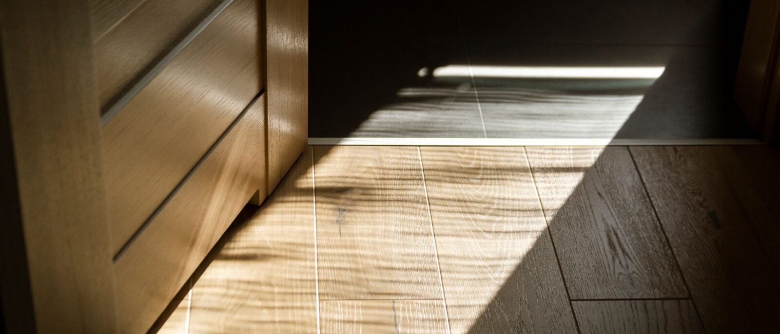 Sombras iluminadas pelo sol criam padrões em um piso de tacos de madeira em ambientes fechados