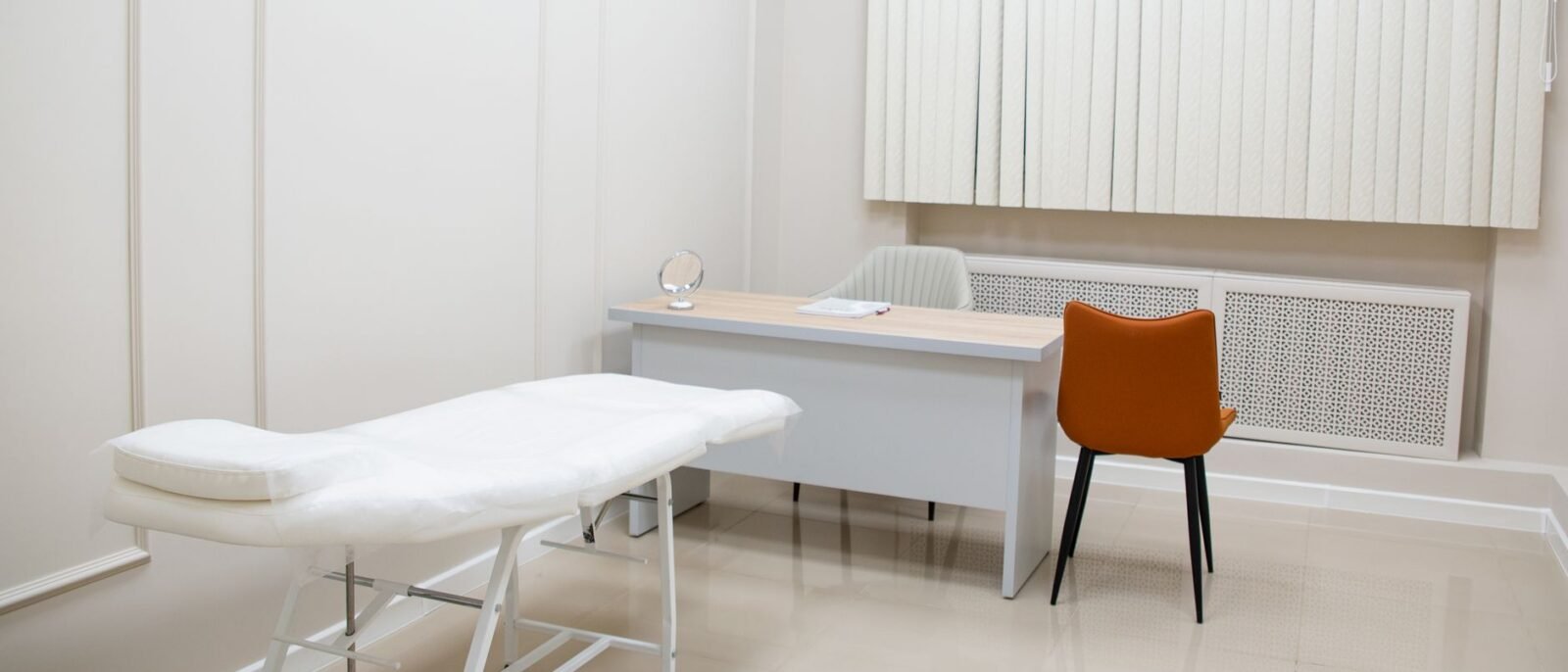 Consultório médico minimalista com escrivaninha, cadeiras e maca de exame em ambiente estéril e neutro